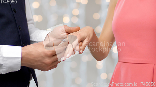 Image of man puts engagement ring on womans finger
