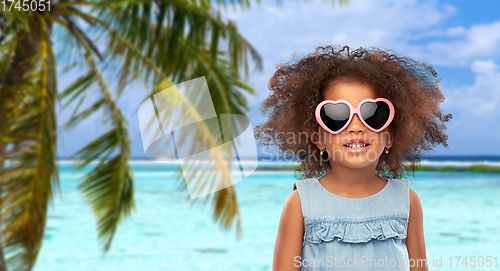 Image of little african girl in sunglasses on beach