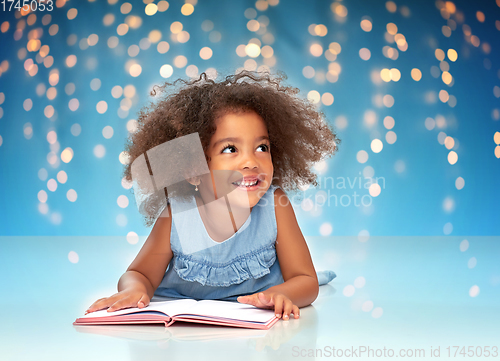 Image of smiling little african american girl reading book