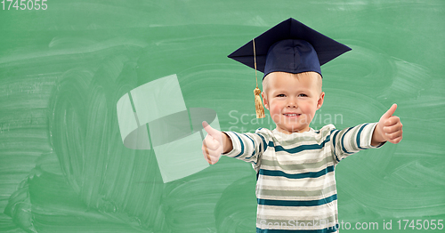 Image of happy little boy in mortar board showing thumbs up