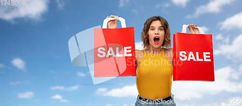 Image of surprised young woman with shopping bags on sale