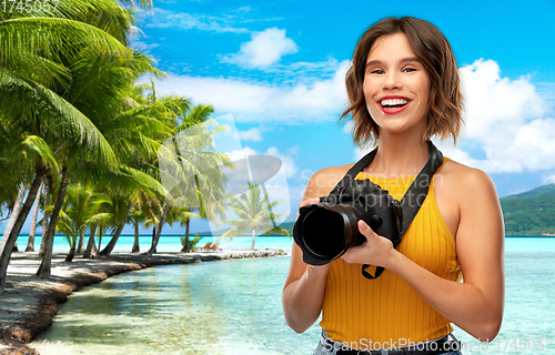 Image of happy woman photographer with camera on beach