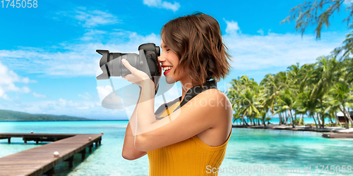 Image of happy woman photographer with camera on beach