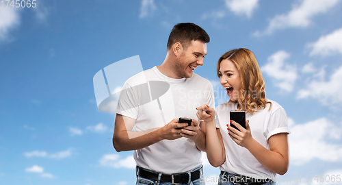 Image of happy couple in white t-shirts with smartphones