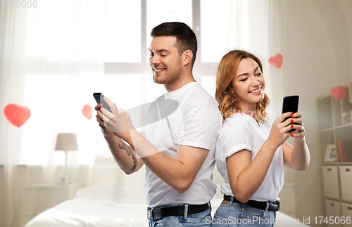 Image of happy couple with smartphones on valentines day