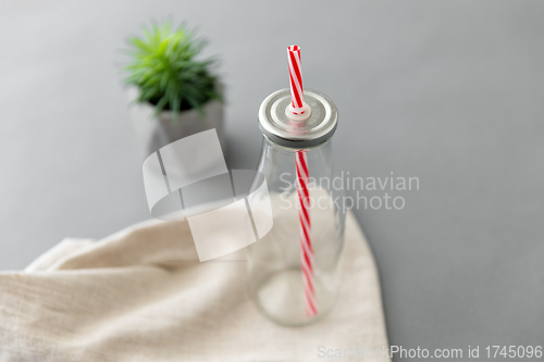 Image of empty reusable glass bottle of with striped straw