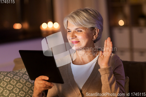 Image of happy senior woman with tablet pc at home at night