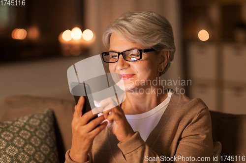 Image of happy senior woman with smartphone at home