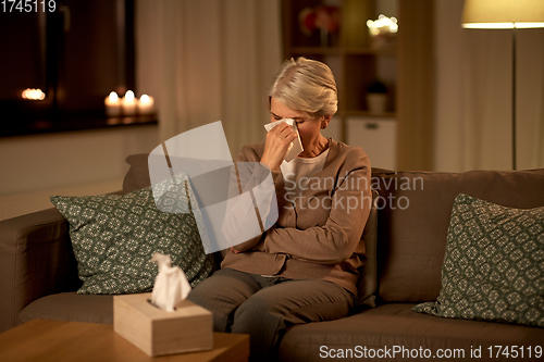 Image of crying senior woman wiping tears with paper tissue