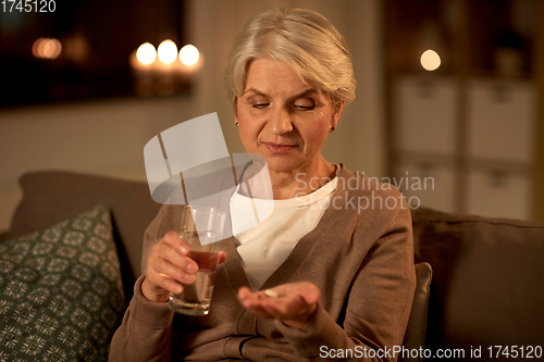 Image of senior woman with water and medicine at home