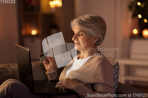 Image of senior woman with laptop and credit card at night