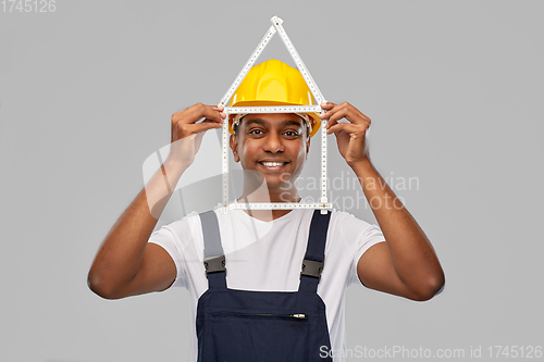 Image of happy indian builder with ruler in shape of home