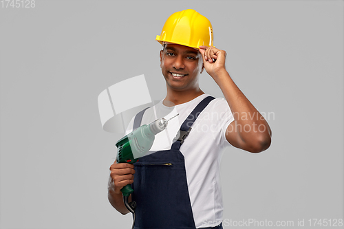 Image of happy indian builder in helmet with electric drill