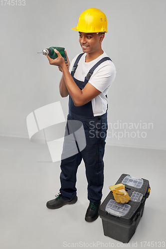 Image of happy indian builder in helmet with electric drill