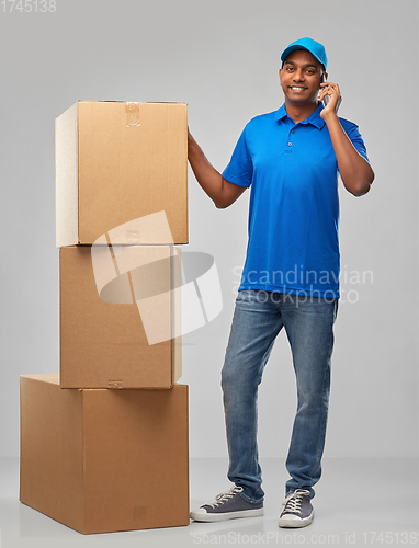 Image of indian delivery man with boxes calls on smartphone