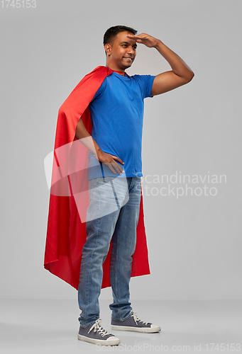 Image of indian man in red superhero cape looking far away