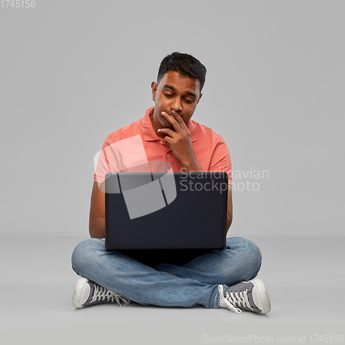 Image of thinking indian man with laptop computer