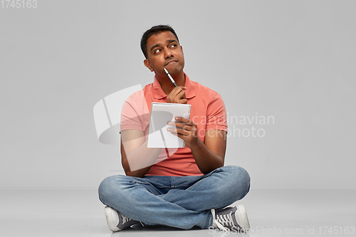 Image of indian man in polo shirt with notebook and pen