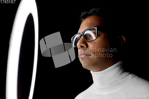 Image of man in glasses at white illumination over black