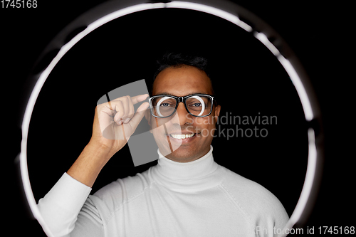 Image of man in glasses over white illumination on black