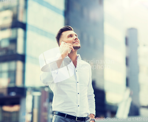 Image of happy man with smartphone calling on city street