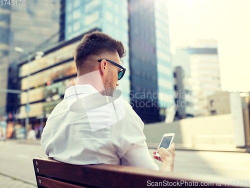 Image of close up of man texting on smartphone in city