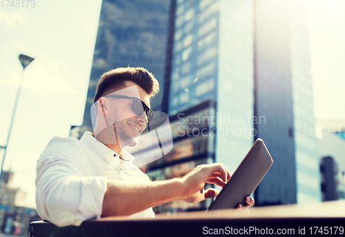 Image of man with tablet pc sitting on city street bench