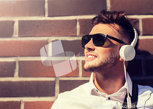 Image of young man in headphones over brickwall