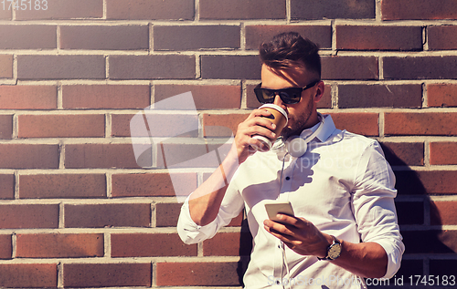 Image of man with smartphone and coffee cup on city street