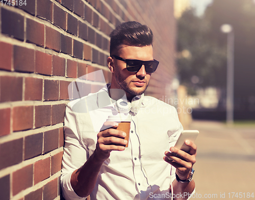 Image of man with smartphone and coffee cup on city street