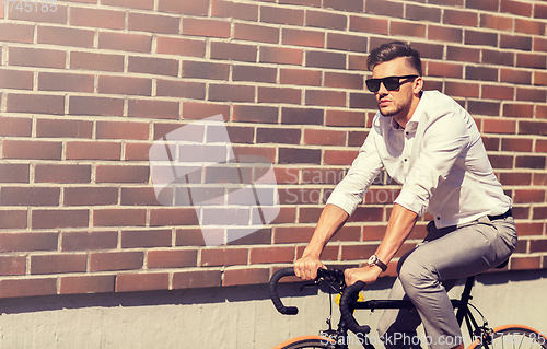 Image of young man riding bicycle on city street