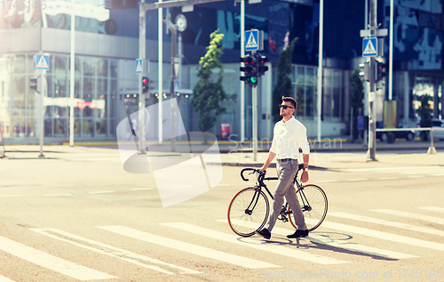 Image of young man with bicycle on crosswalk in city