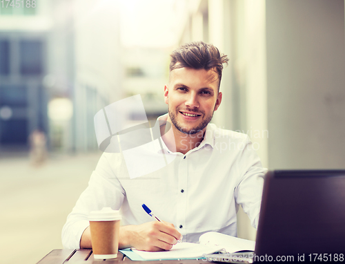 Image of man with laptop and coffee at city cafe