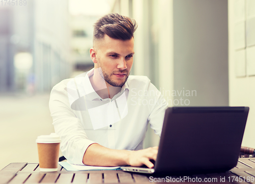 Image of man with laptop and coffee at city cafe