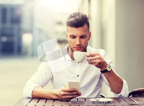 Image of man with smartphone drinking coffee at city cafe