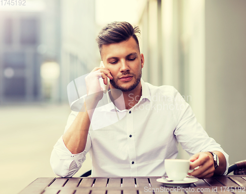 Image of man with coffee calling on smartphone at city cafe