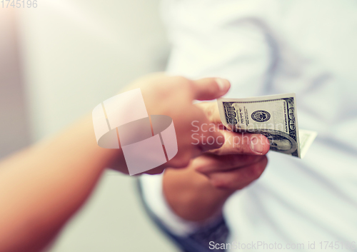 Image of close up of hands giving and receiving dollar money