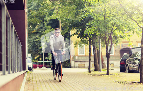 Image of young man riding bicycle on city street