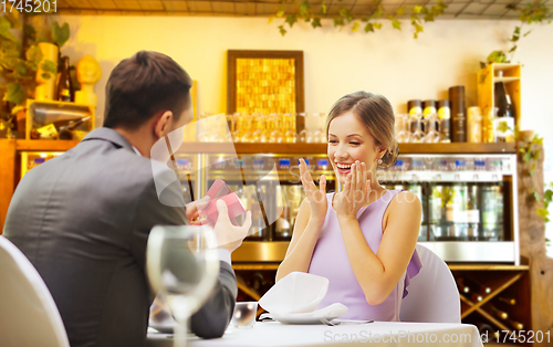 Image of man making proposal to happy woman at restaurant