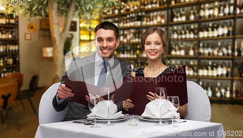 Image of smiling couple with menus at restaurant