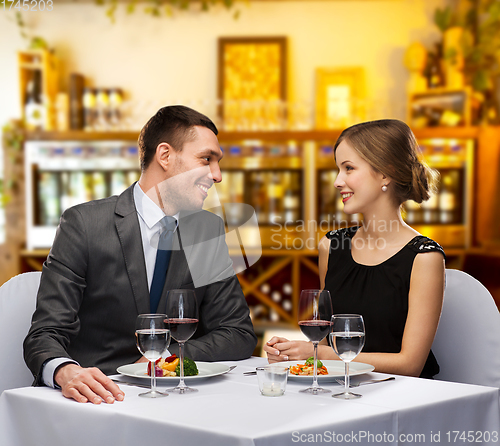 Image of smiling couple with food and wine at restaurant