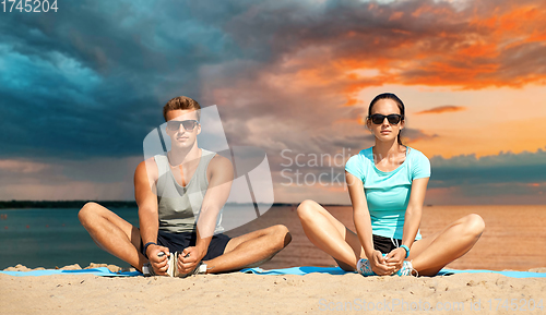 Image of couple stretching legs on beach