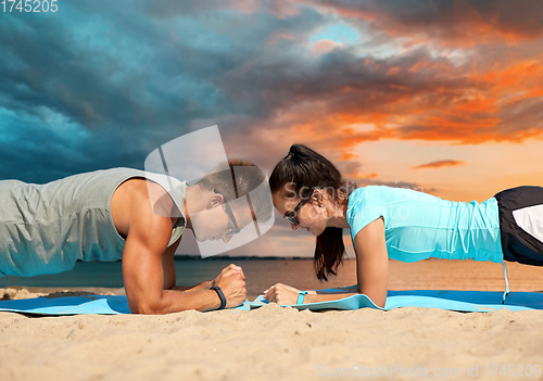 Image of couple doing plank exercise on summer beach