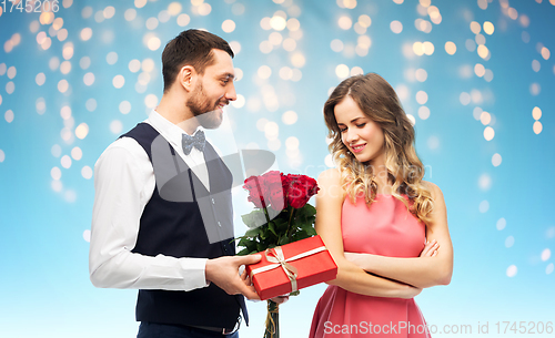 Image of happy man giving woman flowers and present