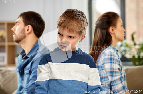 Image of sad little boy with unhappy parents at home