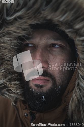 Image of man at winter in stormy weather wearing warm fur jacket