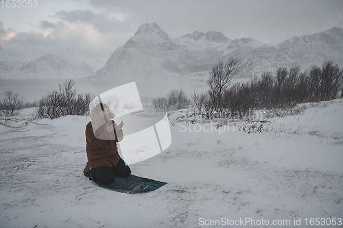 Image of Muslim traveler praying in cold snowy winter day