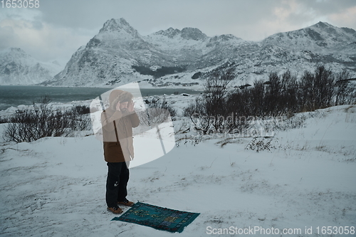 Image of Muslim traveler praying in cold snowy winter day