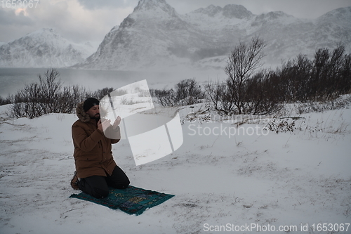 Image of Muslim traveler praying in cold snowy winter day