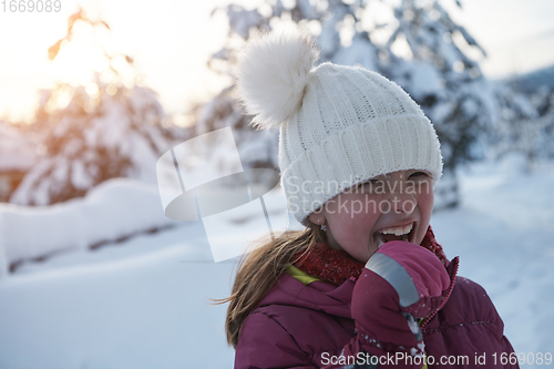 Image of cute little girl while eating icicle on beautiful winter day